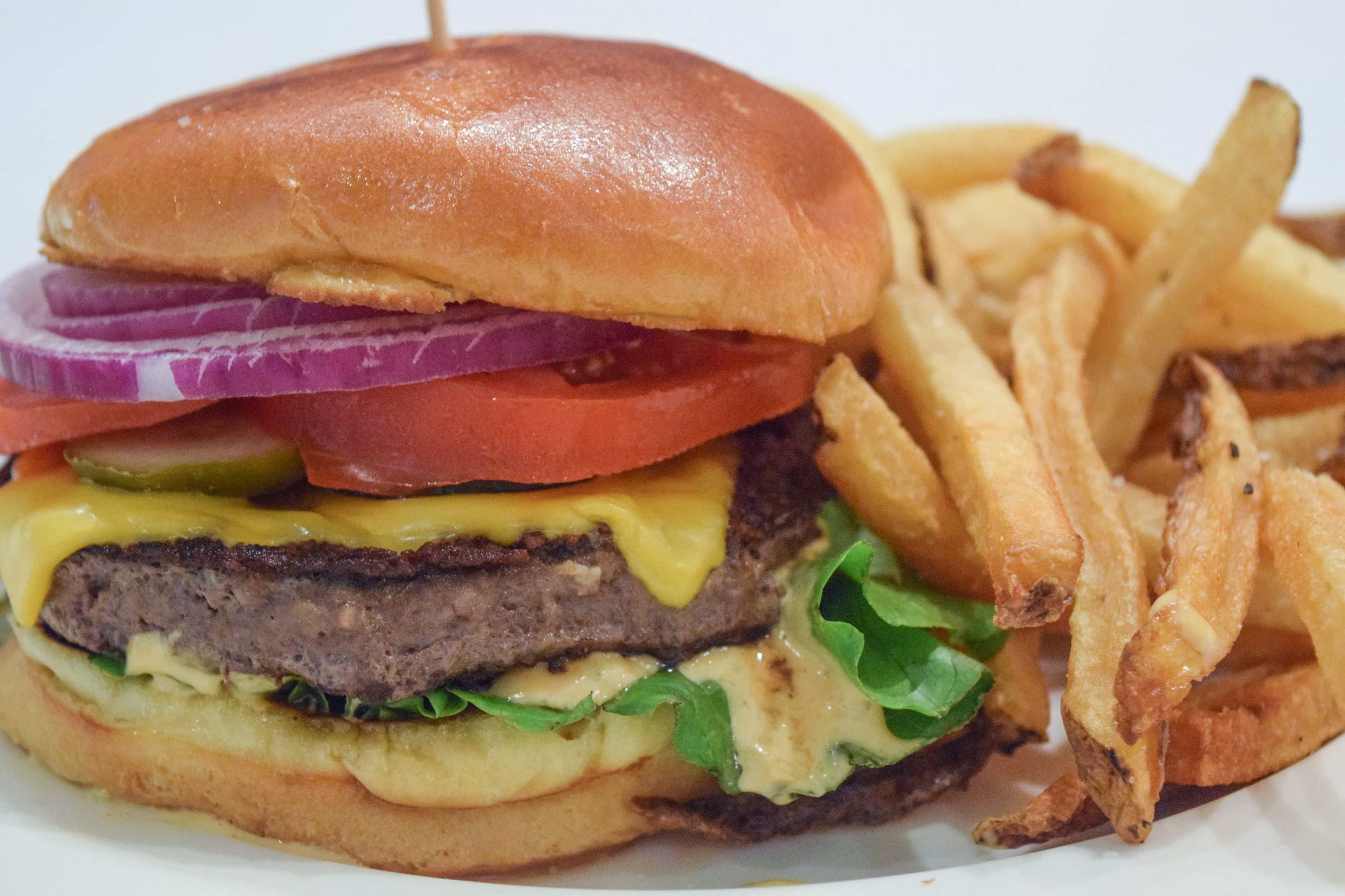A burger with lettuce, tomato, and cheese, and a side of fries.
