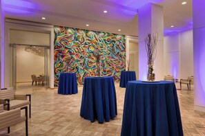 A hotel lobby with a colorful abstract mural, round tables with blue tablecloths, and modern furniture. - Hotel Indigo Atlanta Downtown by IHG (Atlanta)