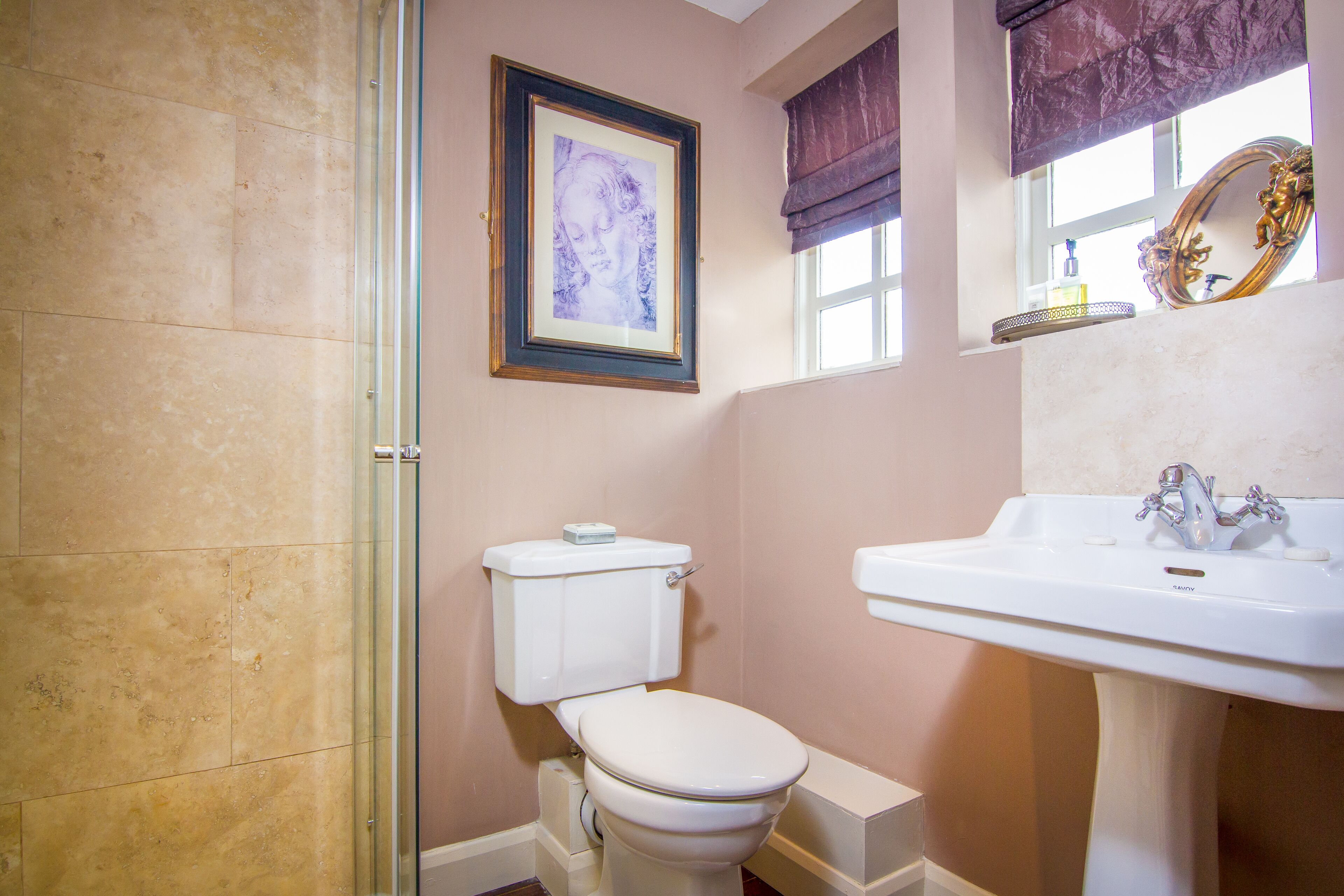 A bathroom with a toilet, a sink, and a framed artwork on the wall.
