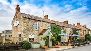 A stone building with a sign for "The Horse Inn" and outdoor seating with umbrellas. - Black Horse Inn  (Northallerton)
