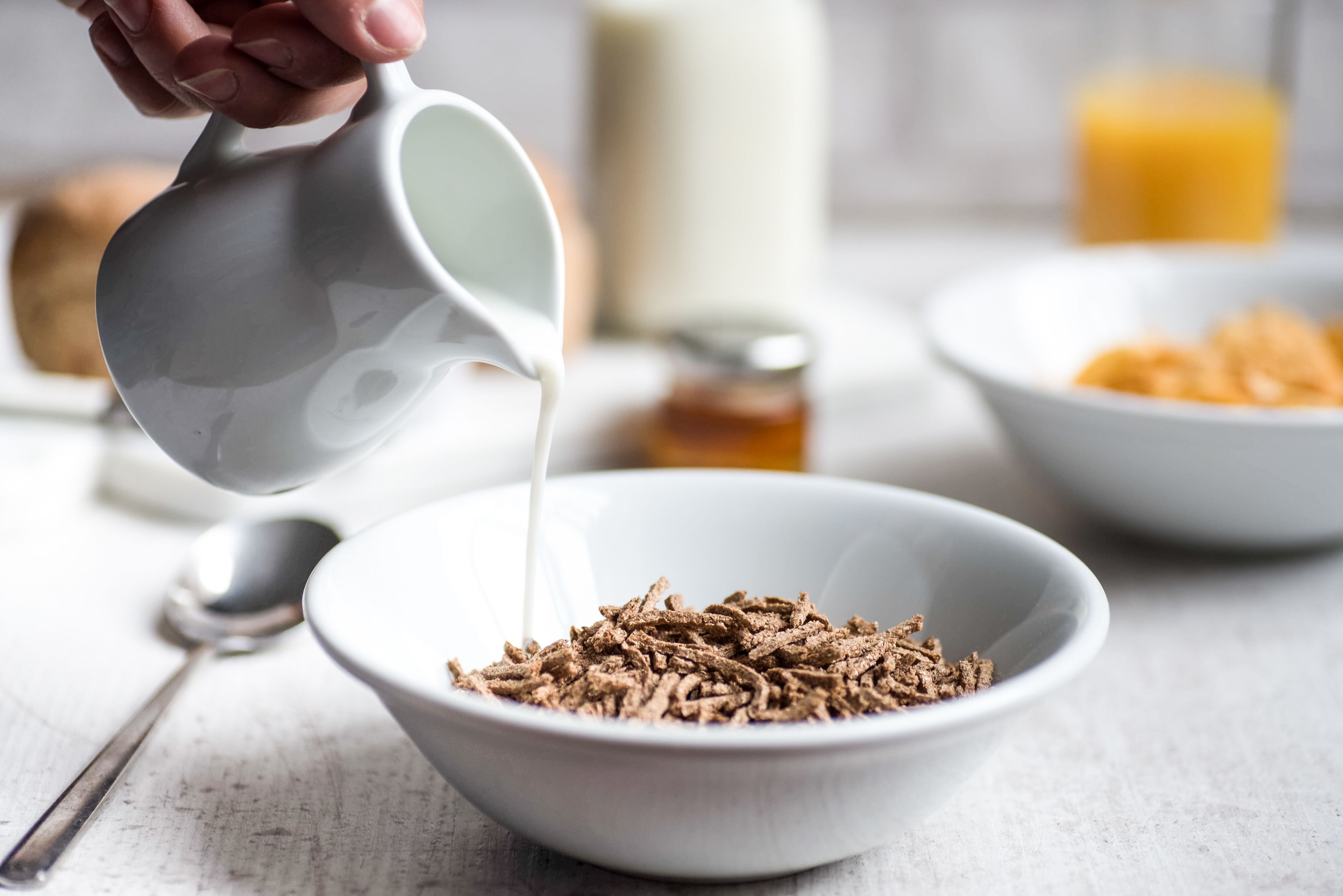 A bowl of cereal with milk being poured into it.