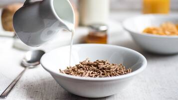 A bowl of cereal with milk being poured into it.
