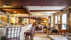 A bar area with stools, a counter, and shelves of bottles. There are tables and chairs in the dining area. - Black Horse Inn  (Northallerton)