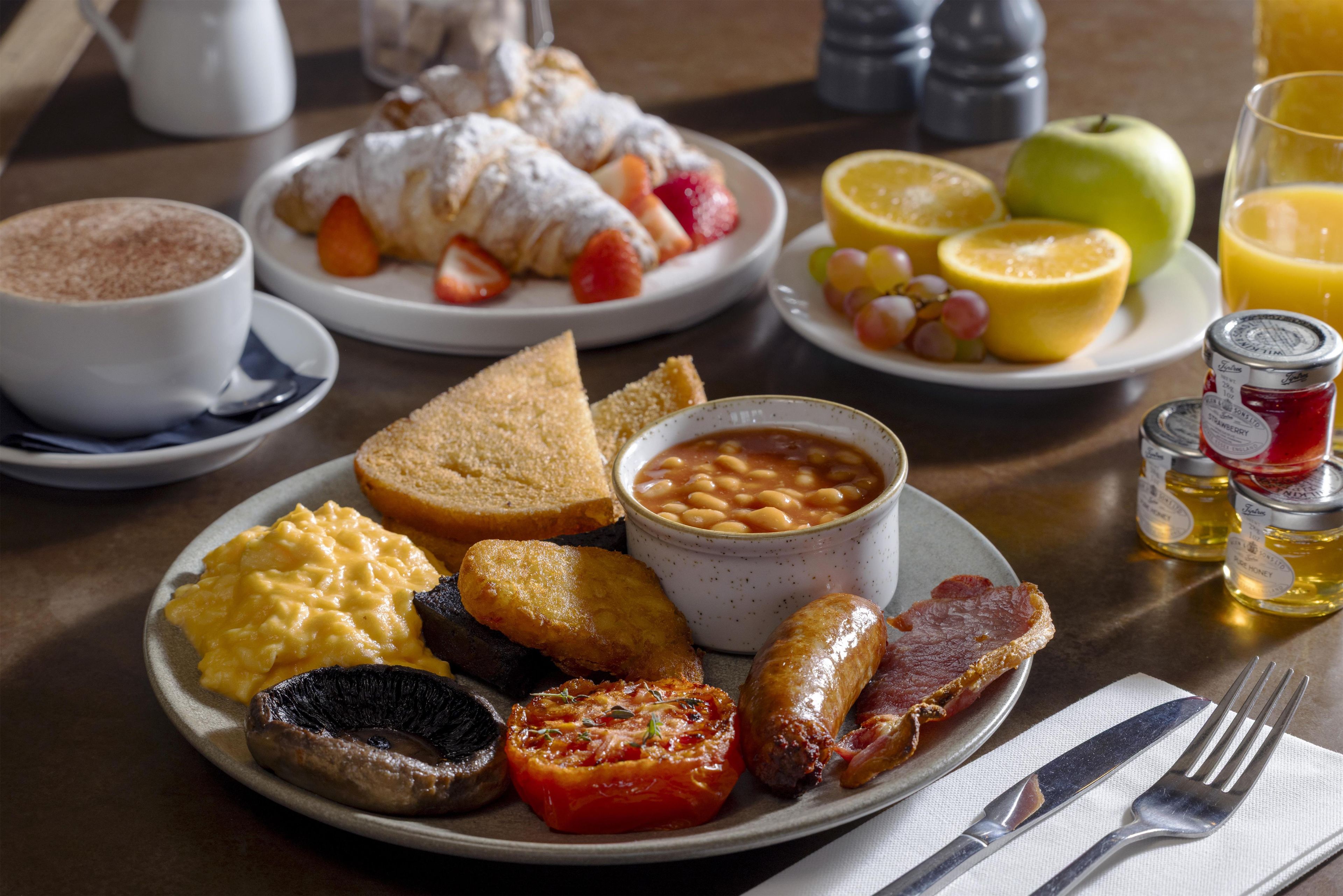 A breakfast plate with eggs, toast, beans, bacon, and tomato.