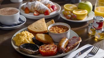 A breakfast plate with eggs, toast, beans, bacon, and tomato.