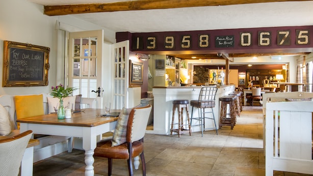 A cozy pub with wooden beams, a chalkboard menu, and a bar area with stools. - Black Horse Inn  (Northallerton)