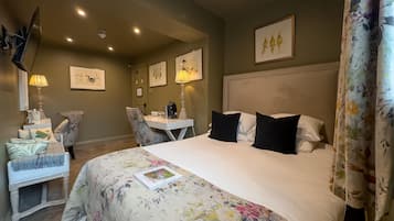 Habitación de hotel con una cama grande, un escritorio con silla, televisor y cuadros en las paredes.