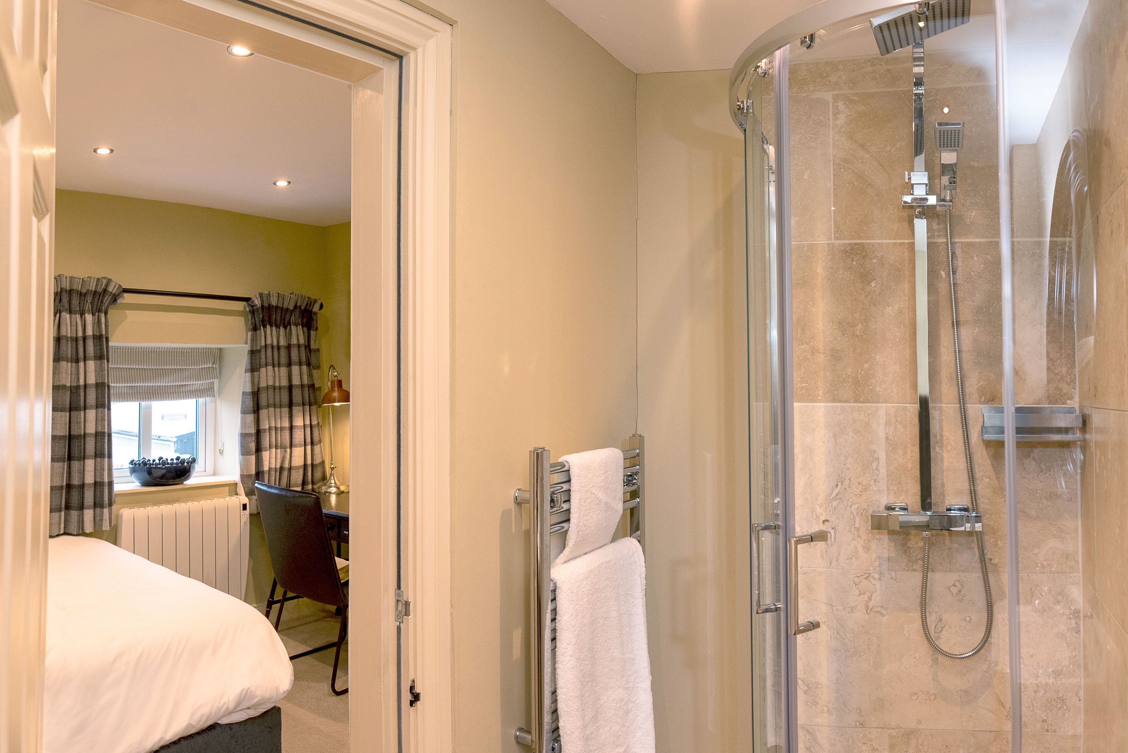 Un bagno moderno con cabina doccia in vetro, un portasciugamani a vista e un termosifone.