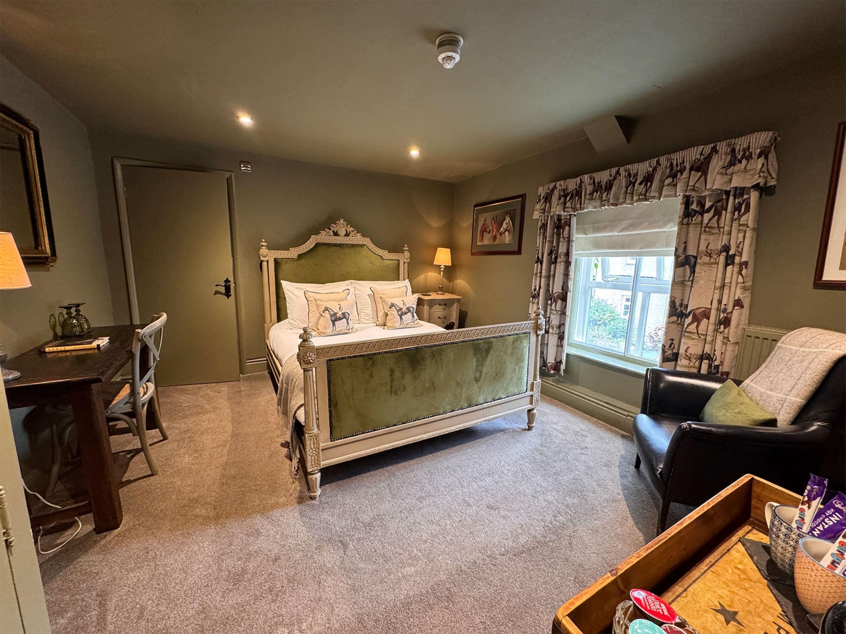 A room with a bed, a desk, a chair, and a window with curtains.