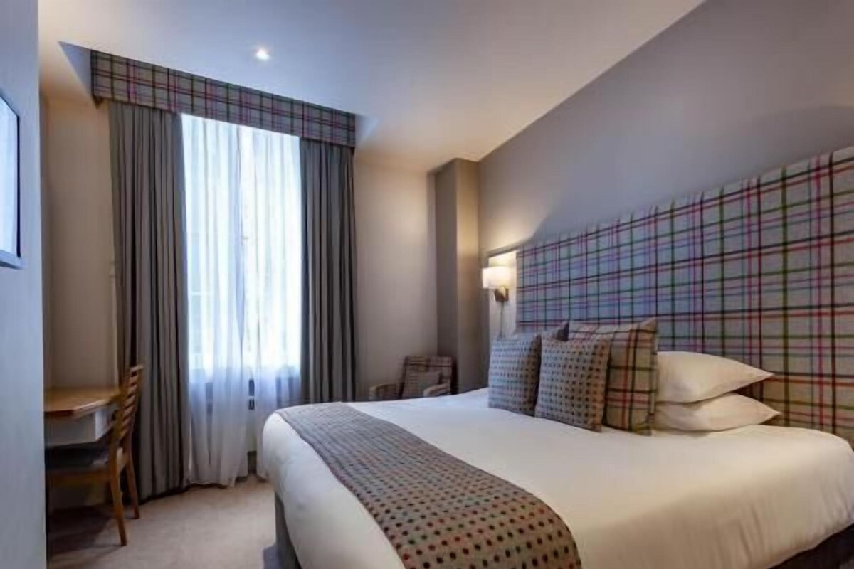 Una habitación de hotel con una cama, un escritorio y una silla.