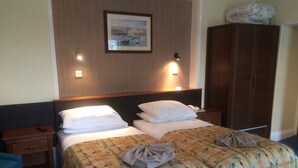 A hotel room with a bed, two bedside tables, a nightstand, a wardrobe, and a framed picture on the wall. - Grange Lodge Hotel (St. Peter Port)