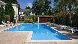 A rectangular swimming pool with a clear blue water surface, surrounded by white lounge chairs and a paved deck. - Grange Lodge Hotel (St. Peter Port)
