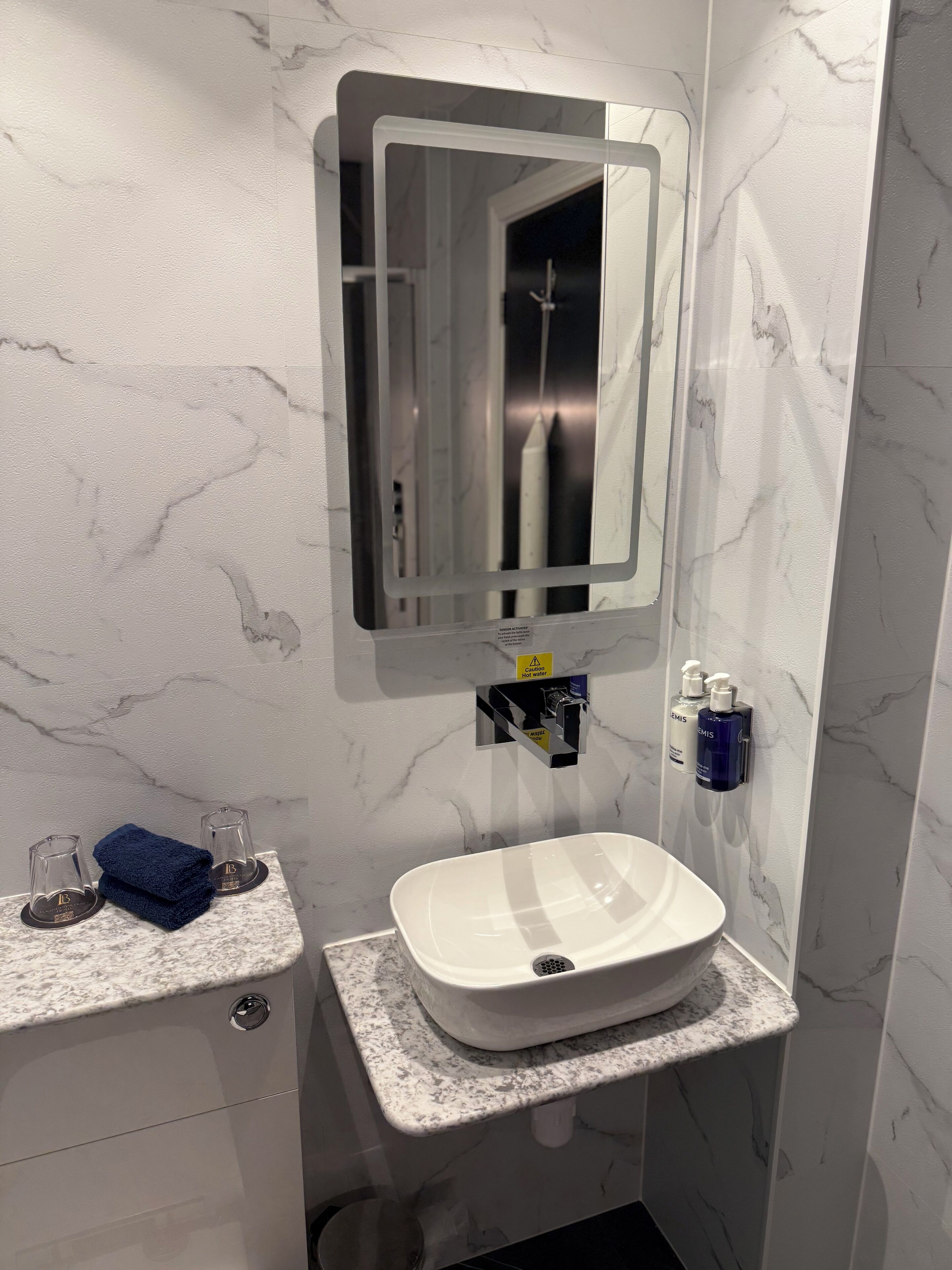 A bathroom with a white sink, a mirror, and toiletries on the wall.