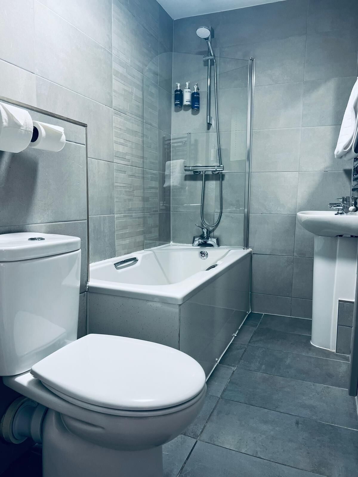 A modern bathroom with a toilet, a bathtub, and a sink.