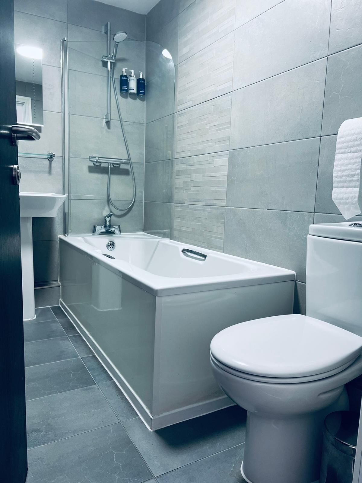 A modern bathroom with a bathtub, toilet, and sink.