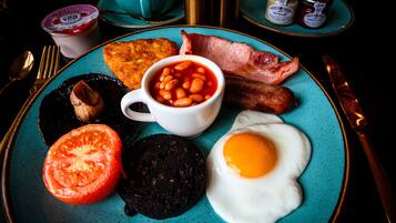A breakfast plate with eggs, bacon, beans, tomato, and black pudding.