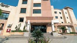 A hotel with a modern facade, a central entrance, and a landscaped front garden. - Swiss Inn Plaza (6th of October City)