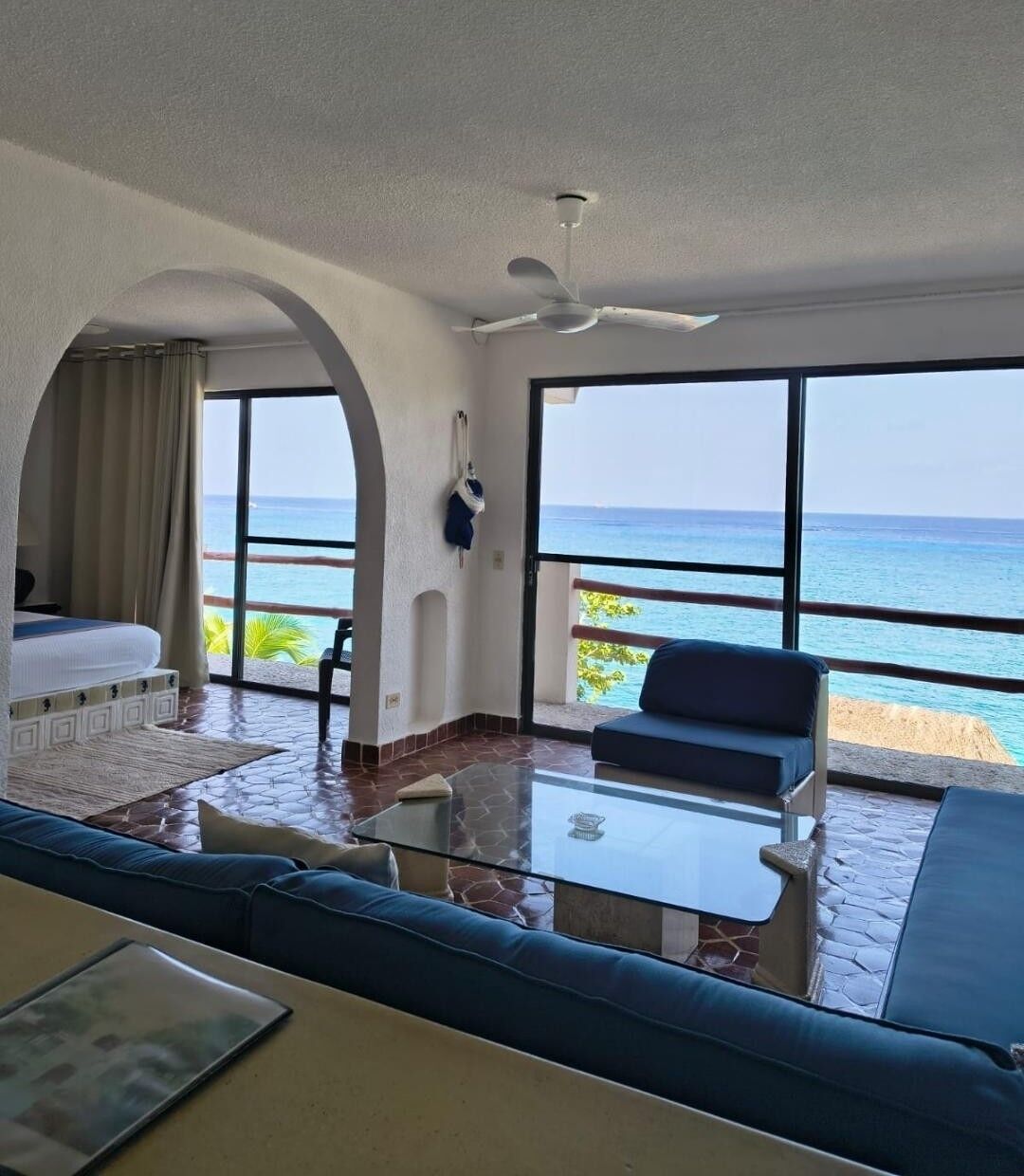 Quarto de hotel com varanda, cama, sofá e mesa.