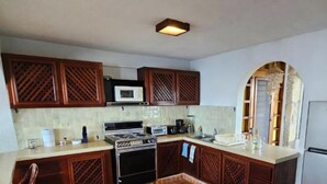 Una cocina con armarios de madera, estufa, microondas y piso de baldosas.