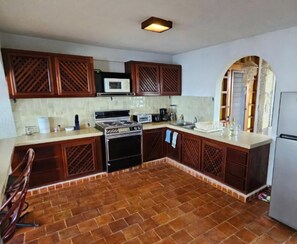 Una cocina con armarios de madera, estufa, microondas y piso de baldosas.