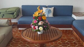 Una sala de estar con un sofá azul, una mesa de centro redonda de madera y un piso de baldosas.