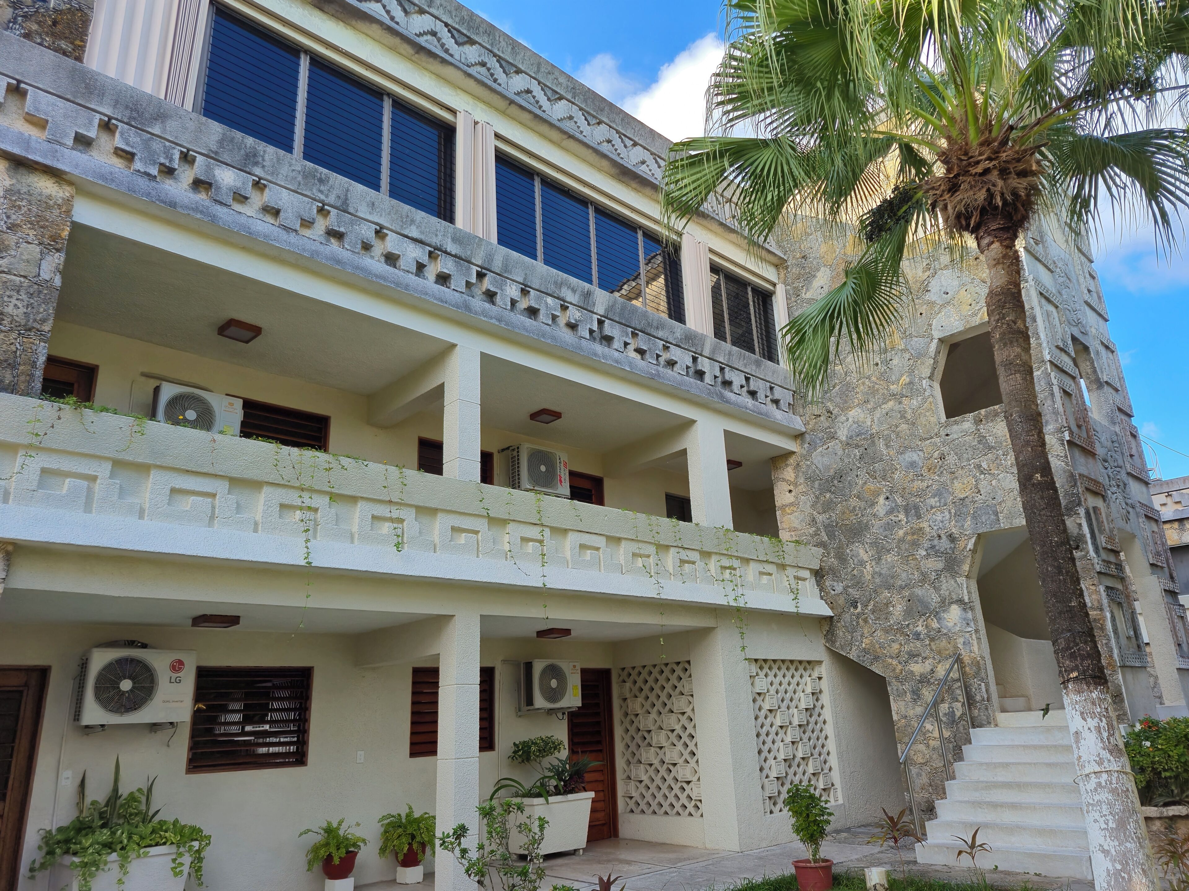 A multi-story building with balconies, air conditioning units, and potted plants.