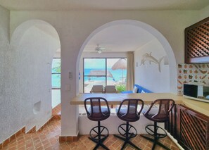Cozinha com vista para a praia, ventilador de teto e micro-ondas.