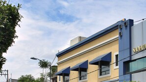 Un edificio de dos pisos con fachada amarilla y detalles azules, que cuenta con una tienda visible y letreros.