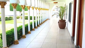 A corridor with white columns, a potted plant, and a tiled floor. - Aldea del Bazar (Tehuacán)