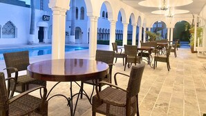 A covered outdoor area with a pool, dining tables, wicker chairs, and a spa sign. - Aldea del Bazar (Tehuacán)