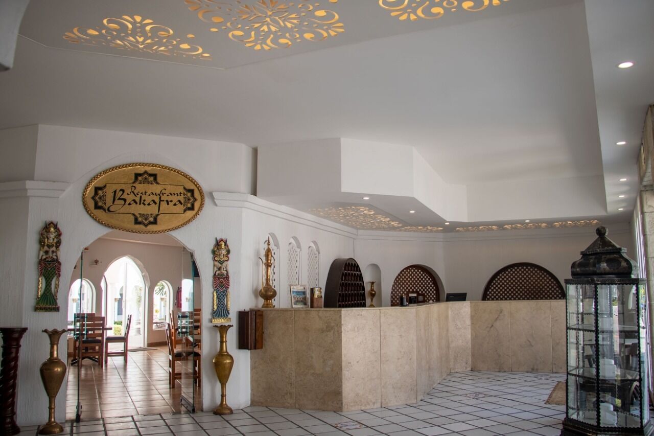A lobby with a reception desk, decorative arches, and a chandelier.