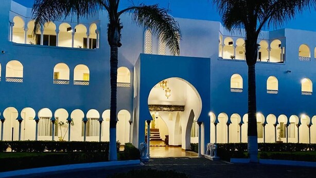 A building with a blue facade, multiple arches, and a central entrance. - Aldea del Bazar (Tehuacán)