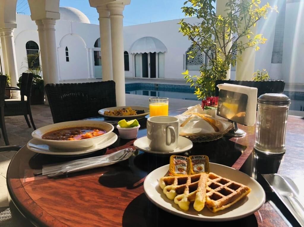 Ein Frühstückstisch mit einer Suppenschüssel, Waffeln, einer Tasse Kaffee und einem Glas Orangensaft.