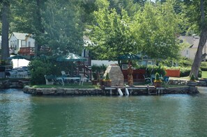 A lakeside setting with outdoor seating, a stone feature, and a dock. - Channel Watefront Cottages (Laconia)
