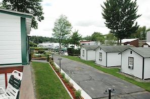 A row of white single-story houses with a paved driveway and a grassy area in front. - Channel Watefront Cottages (Laconia)