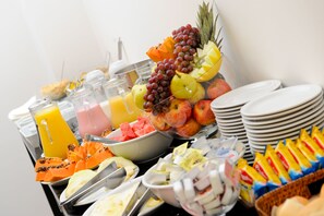 Un bufé con diversas frutas, zumos y productos para el desayuno.
