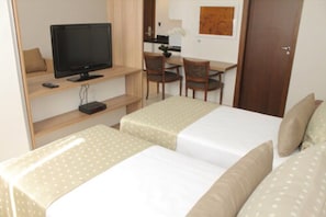 Une chambre d’hôtel avec deux lits, une télévision, un bureau et une chaise.