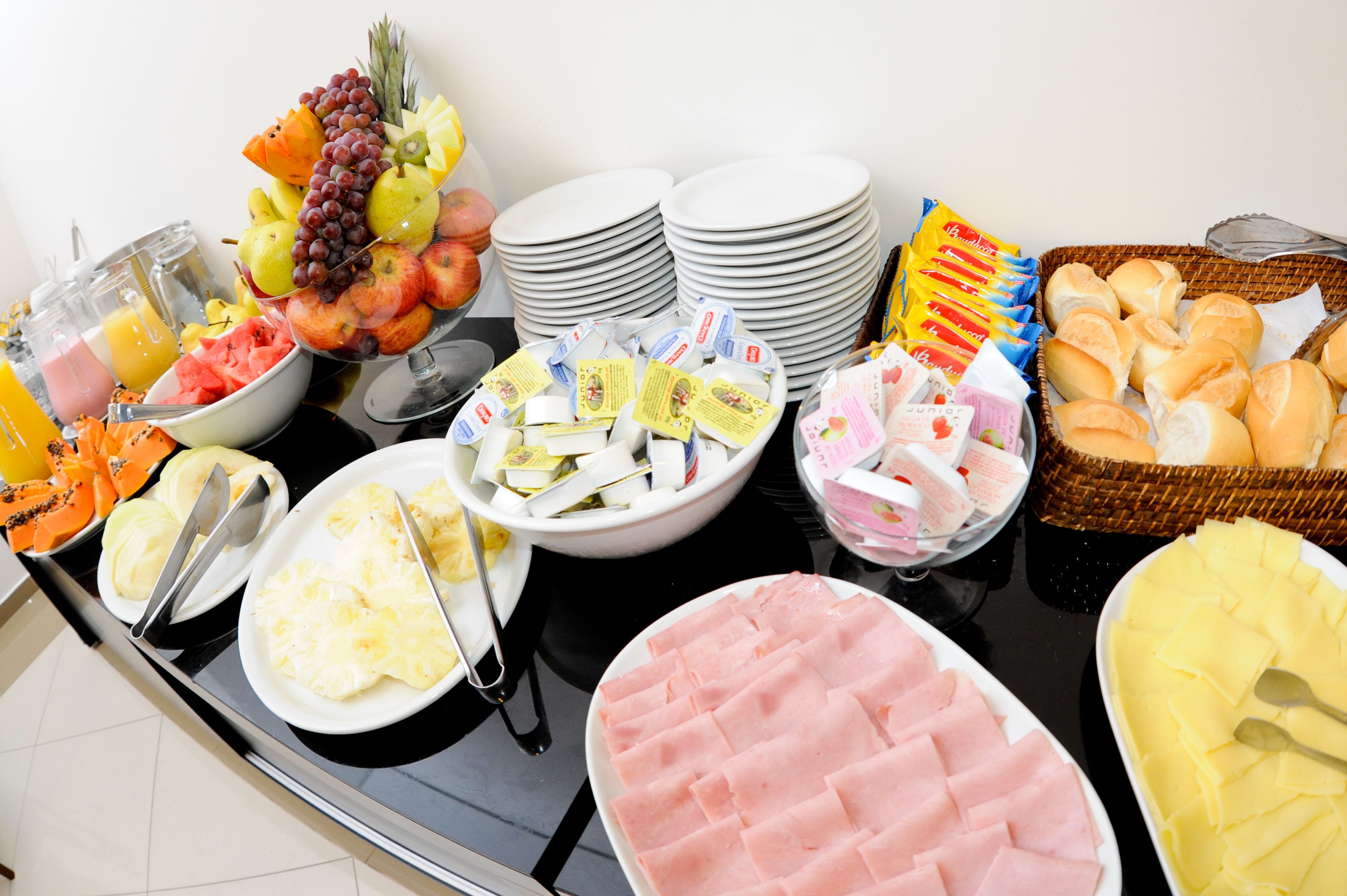 Un buffet proposant une variété d’aliments, notamment des fruits, des sandwichs et des pâtisseries.