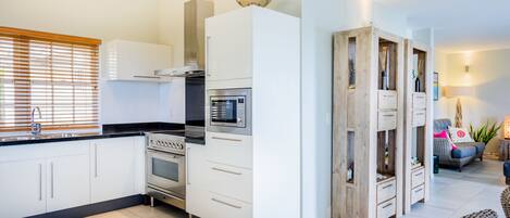 A modern kitchen with white cabinets, a built-in oven, and a microwave.