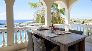 A dining area with a table set for two, overlooking a marina with boats and palm trees. - Curacao Luxury Holiday Rentals (Willemstad)
