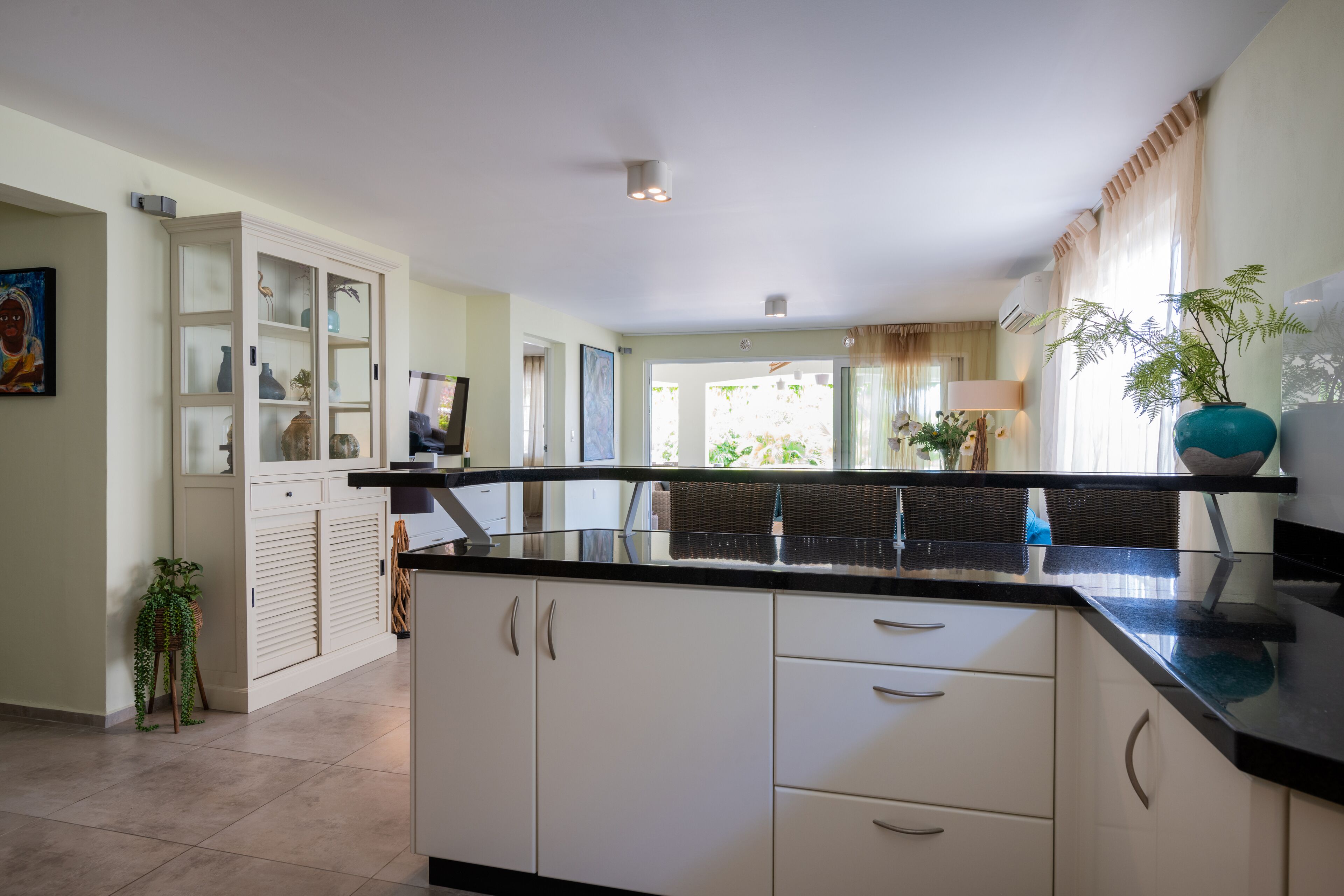 A modern kitchen with white cabinets, black countertops, and a large window.