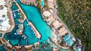 An aerial view of a coastal resort with clear turquoise waters, a marina, and a variety of buildings including villas and a hotel. - Curacao Luxury Holiday Rentals (Willemstad)