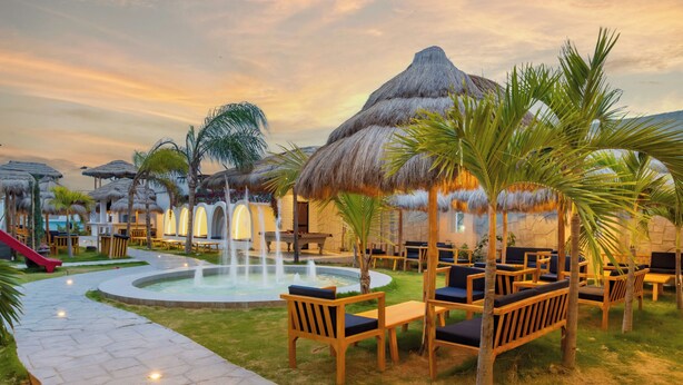 A resort pool area with thatched-roof structures, lounge chairs, and a pathway. - Presidente Beach (Salinas)