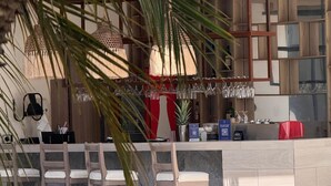 A modern bar area with wooden stools, a counter with a QR code, and a backdrop of a wooden slatted wall. - Presidente Beach (Salinas)