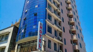 A hotel with a blue glass facade and a sign indicating it is a hotel. - Rainbow Hotel (Dar es Salaam)