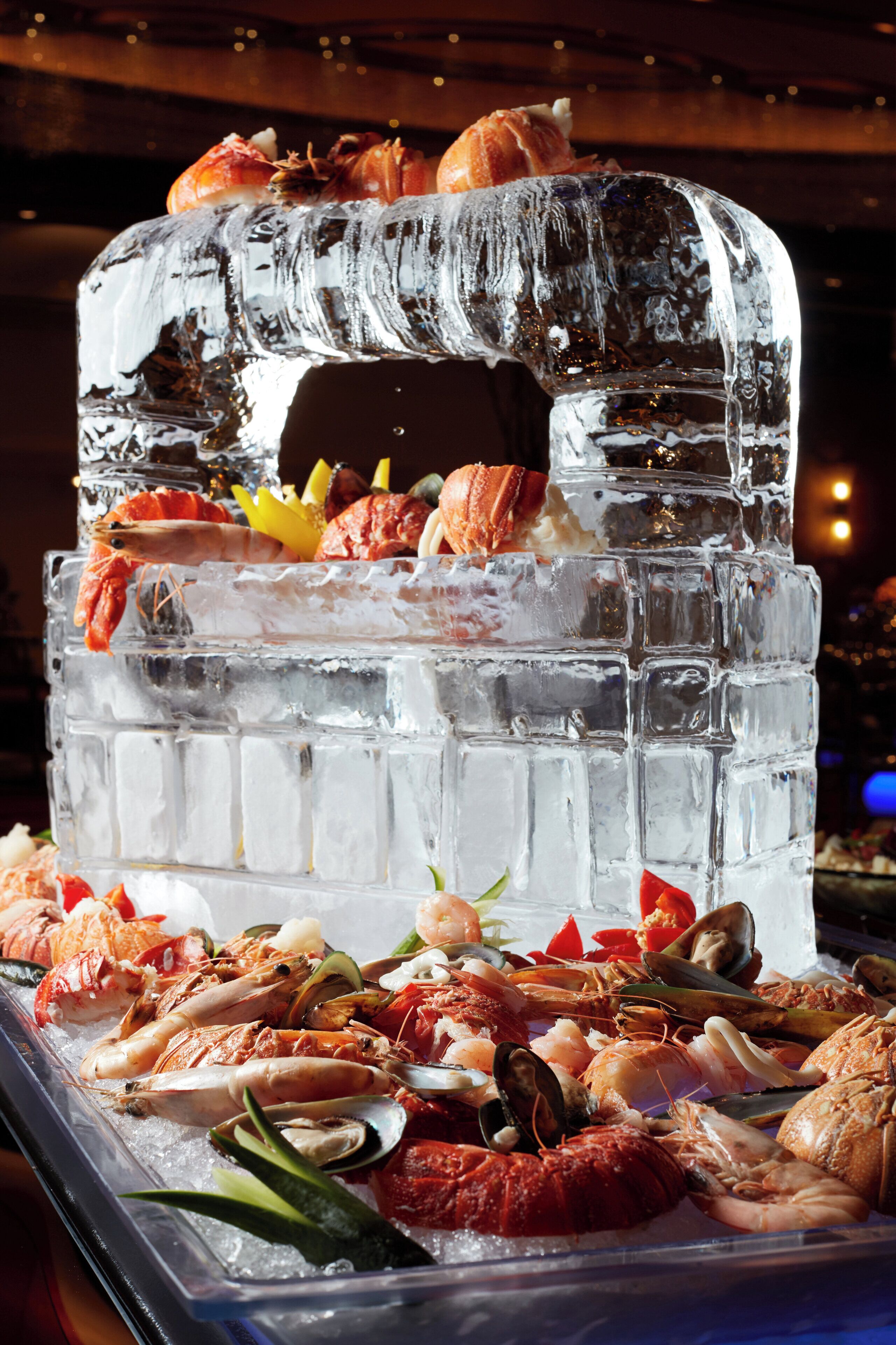 An ice sculpture with seafood on top and a variety of seafood displayed on ice below.