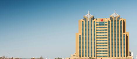 A tall, modern hotel with a symmetrical facade, featuring a central entrance and two symmetrical towers with spires.