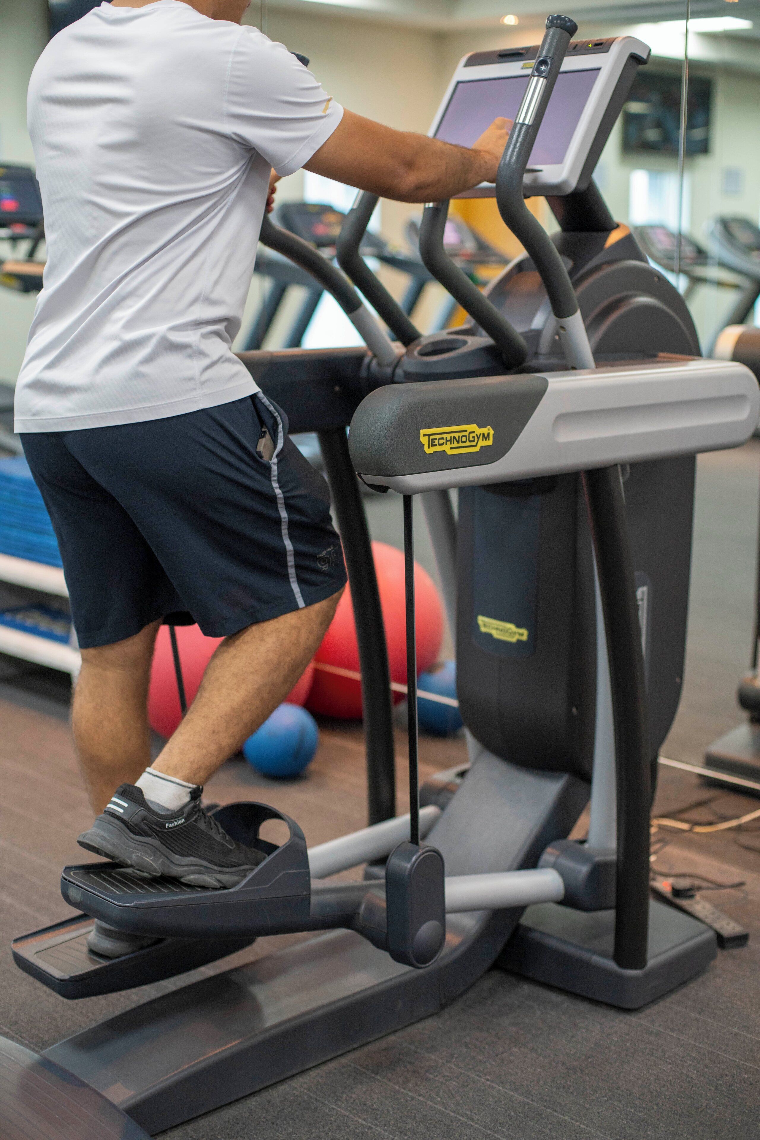 A man using a treadmill in a gym with exercise balls in the background.