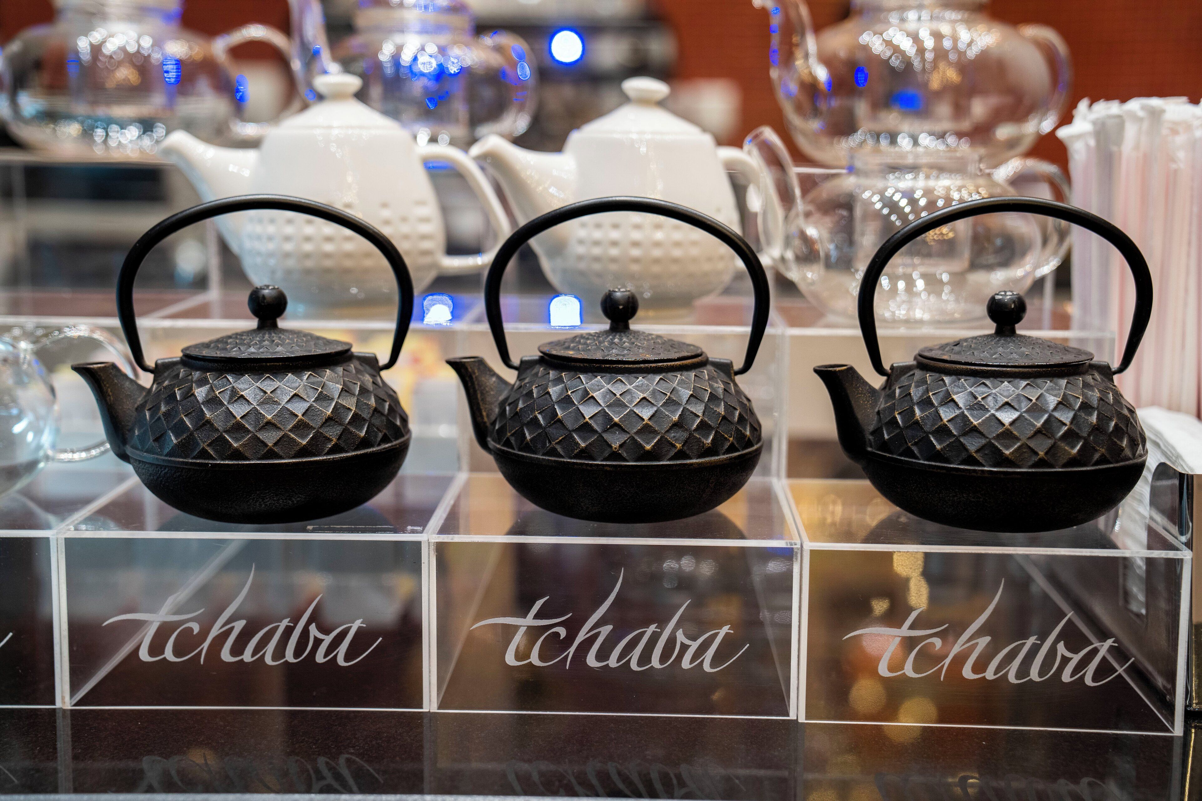 Trois théières noires ornées de couvercles à motifs losangés sont exposées, et chacune porte l’étiquette « tchaba ».