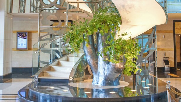 A modern lobby with a central glass sculpture, a curved staircase, and a polished marble floor. - Millennium Hotel and Convention Centre Kuwait (Salmiya)